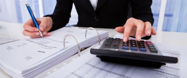 Businesswoman Calculating Tax Midsection of businesswoman calculating tax at office desk